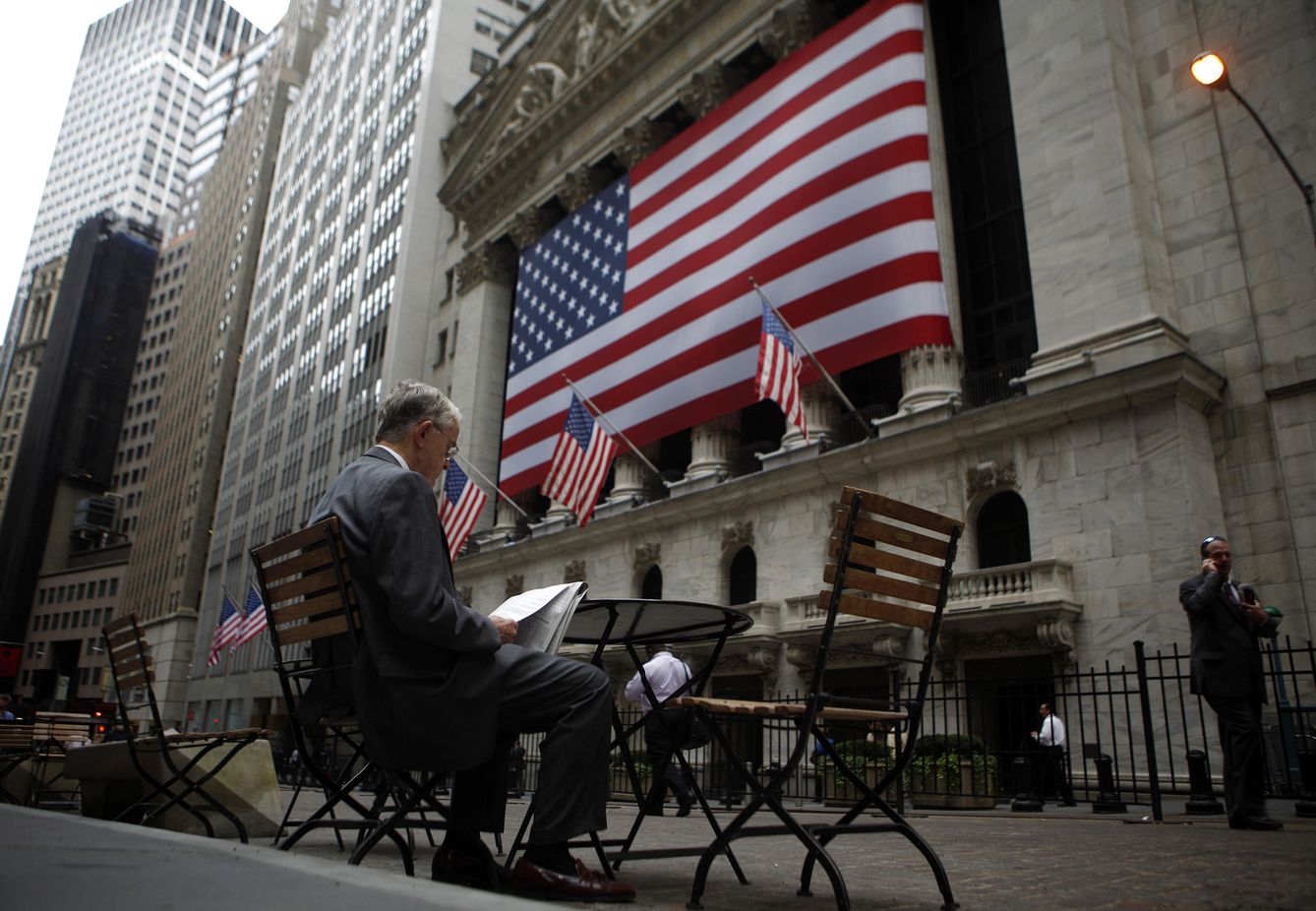 Un hombre lee un diario ante la Bolsa de Nueva York (Reuters).