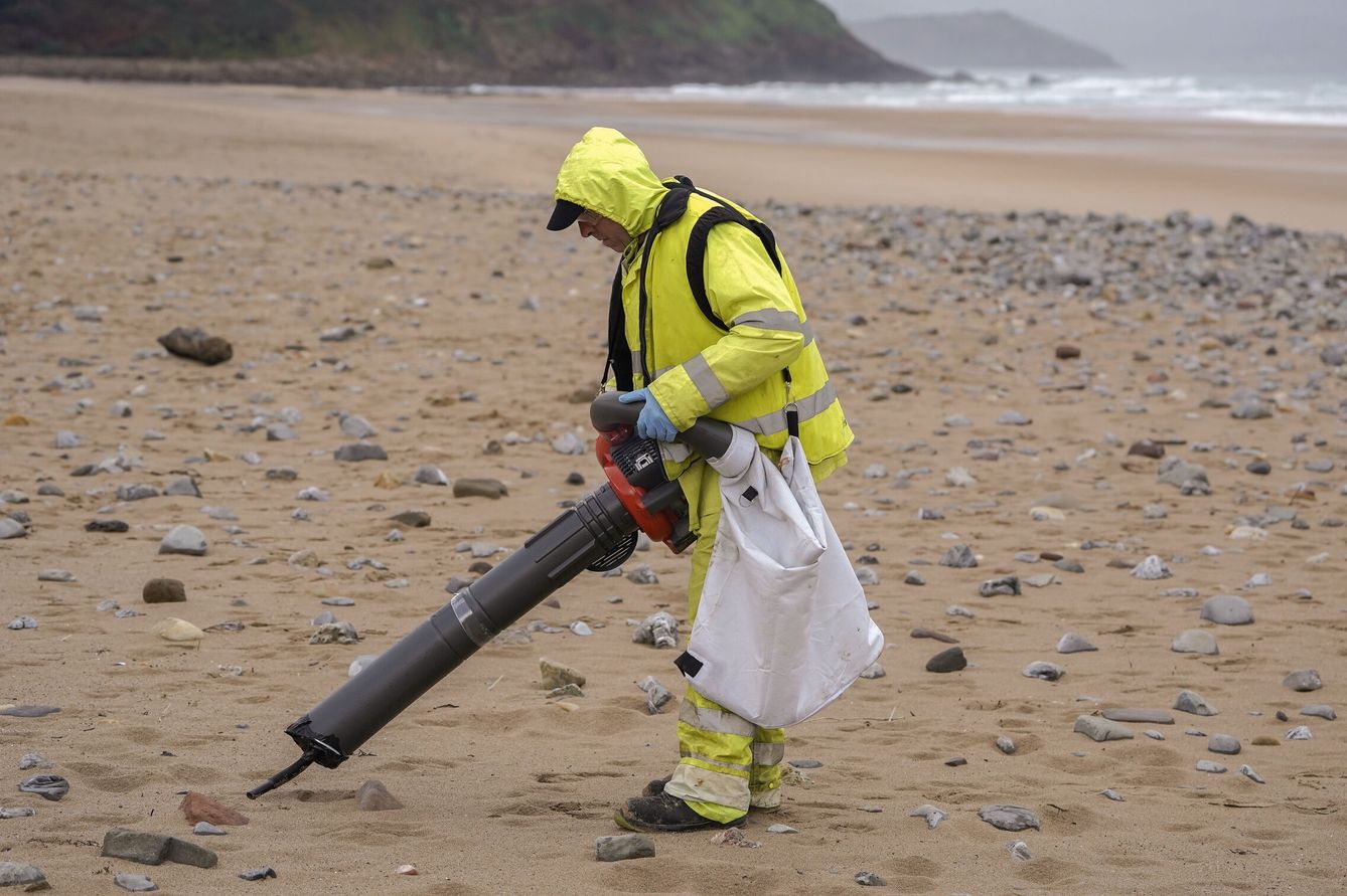 Un operario recoge 'pellets' de plástico este jueves en la playa de Vega, Asturias. (EFE/Paco Paredes)