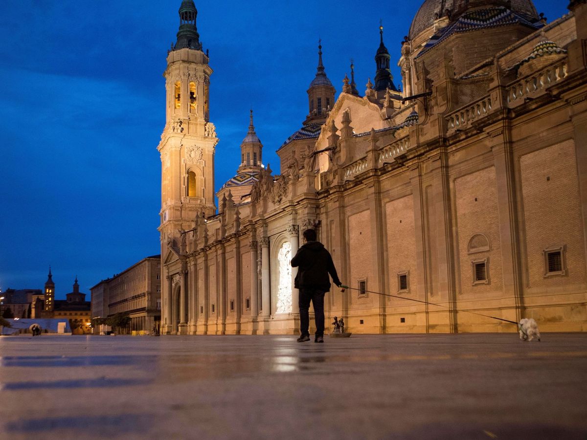 Foto: Un hombre pasea en una vacía plaza del Pilar de Zaragoza. (EFE/Toni Galán)