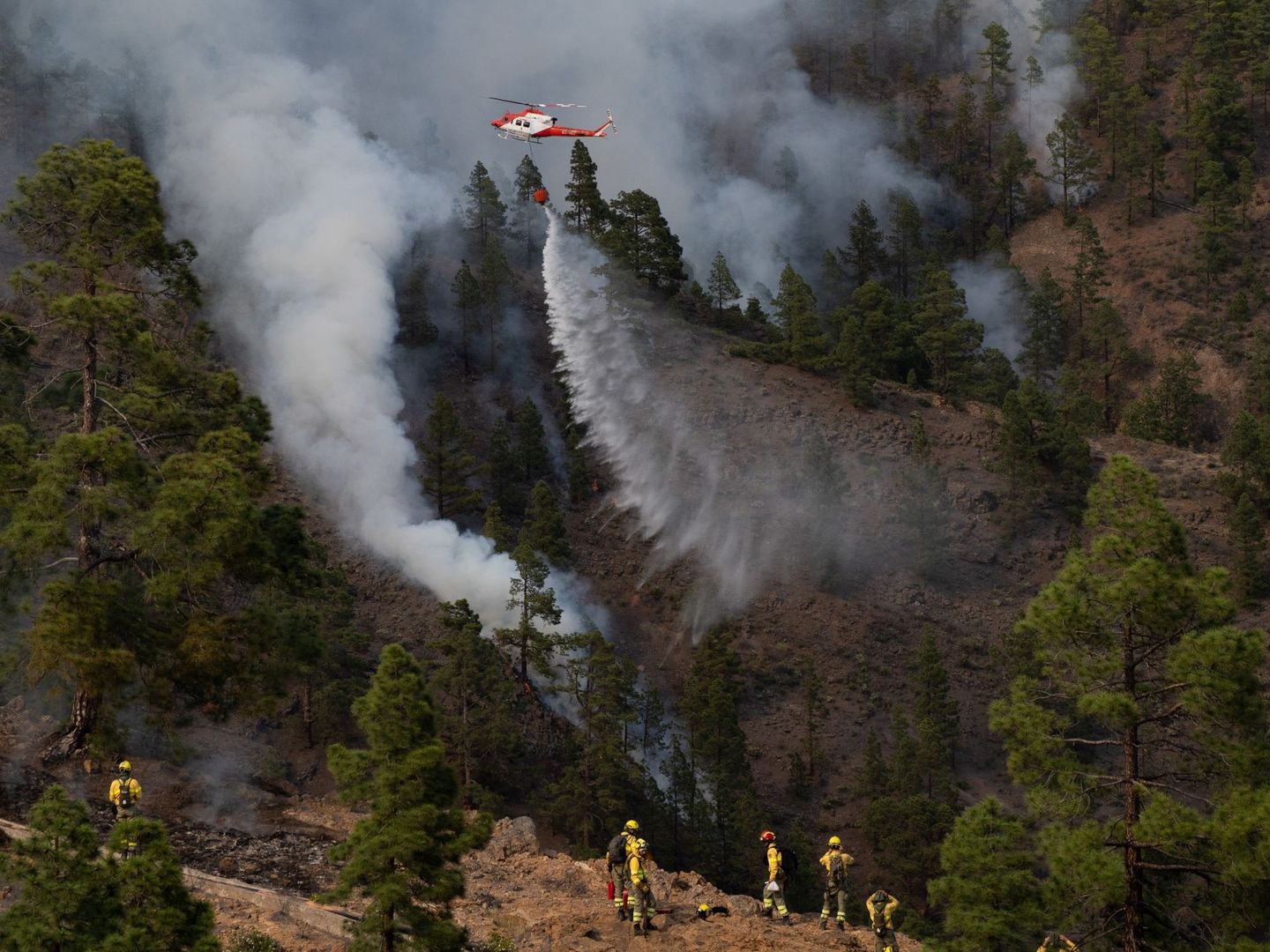 Un helicóptero descarga agua sobre una de las zonas del incendio. (EFE)