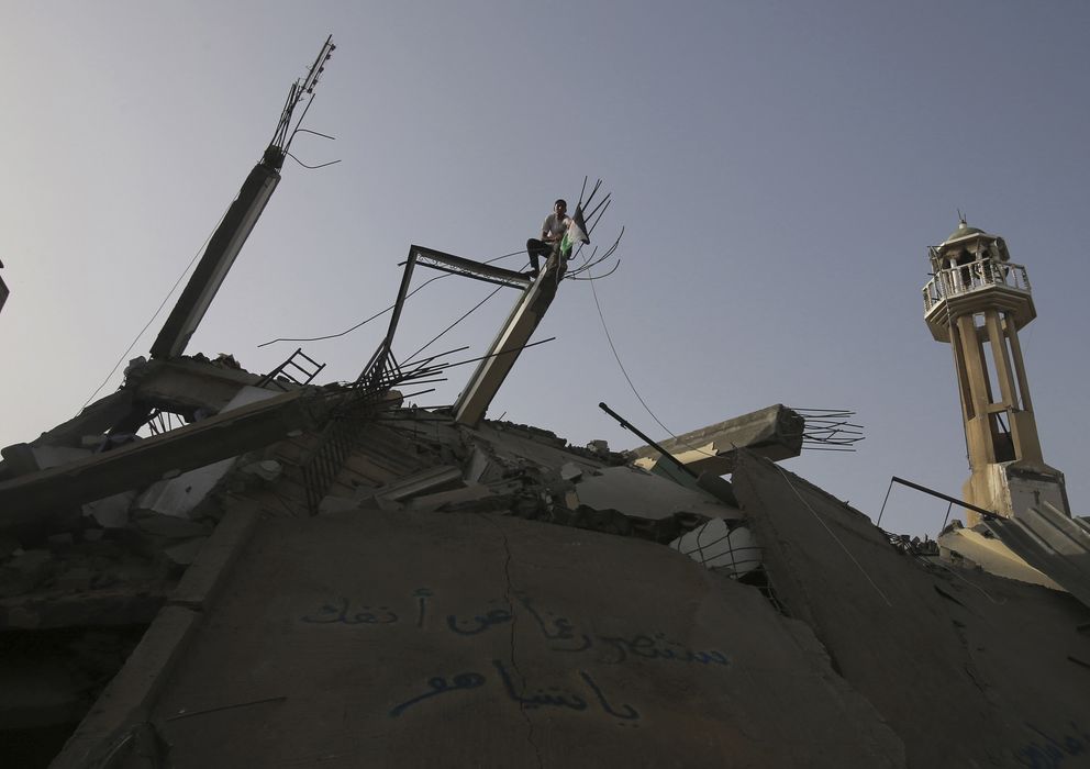 Foto: Un joven coloca una bandera palestina sobre las ruinas de una mezquita en Nuseirat, en el centro de la Franja de Gaza (Reuters).