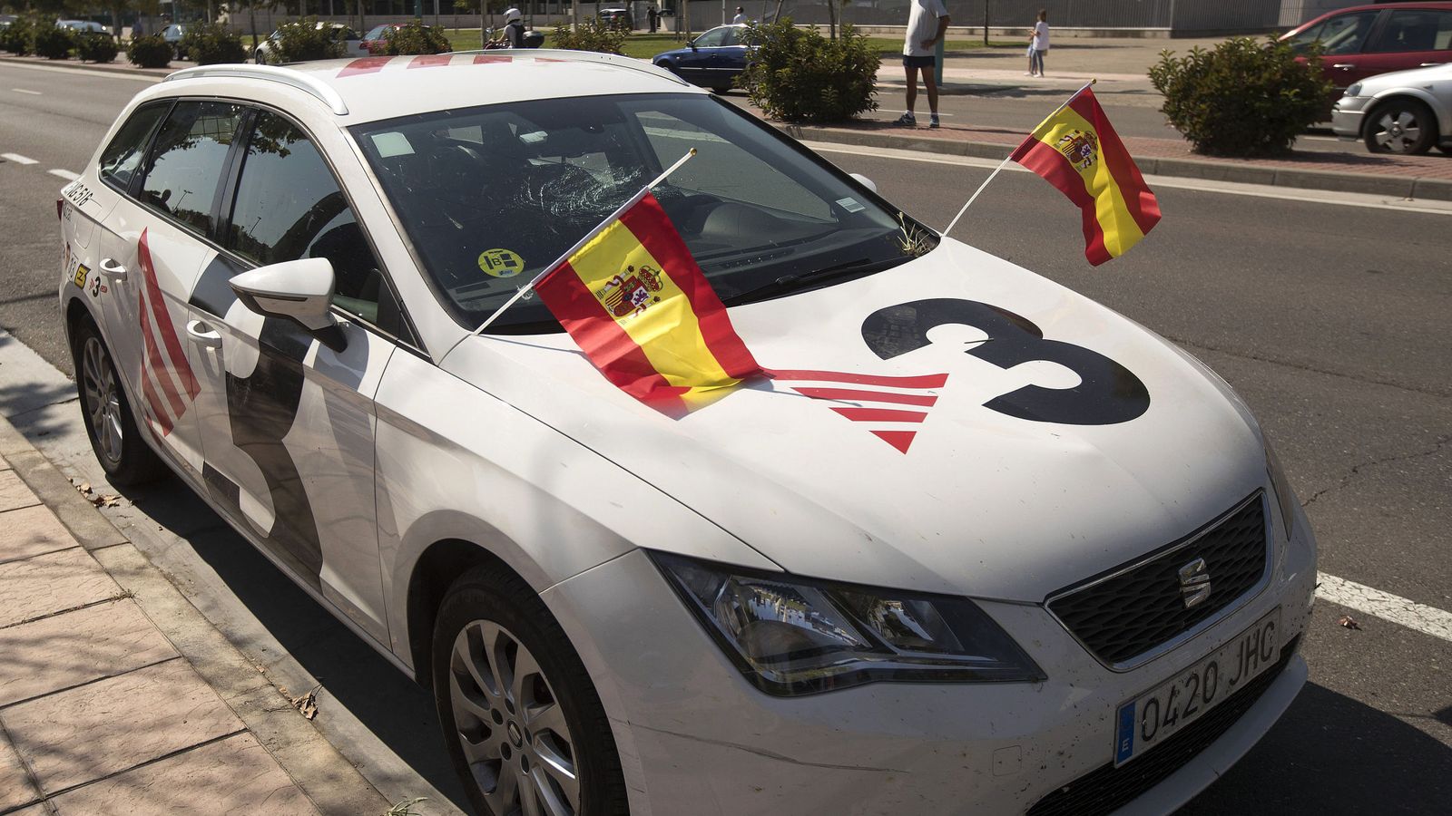 Foto: Un coche de TV3, con la luna rota y en el que los manifestantes han colocado dos banderas de España. (EFE)