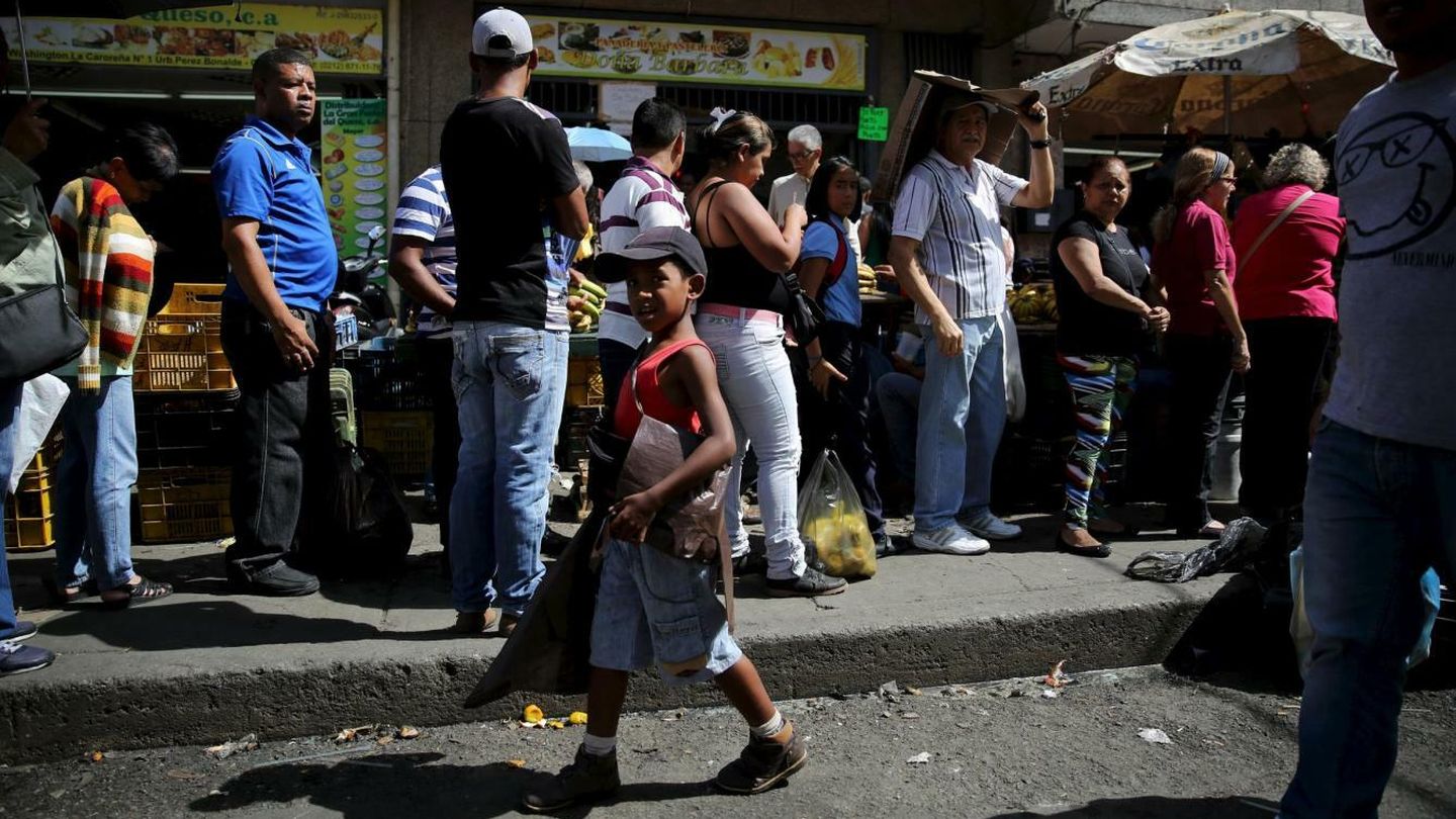 Un niño vende bolsas de plástico a las personas que hacen cola para comprar pollo en Caracas, el 8 de diciembre de 2015 (Reuters).