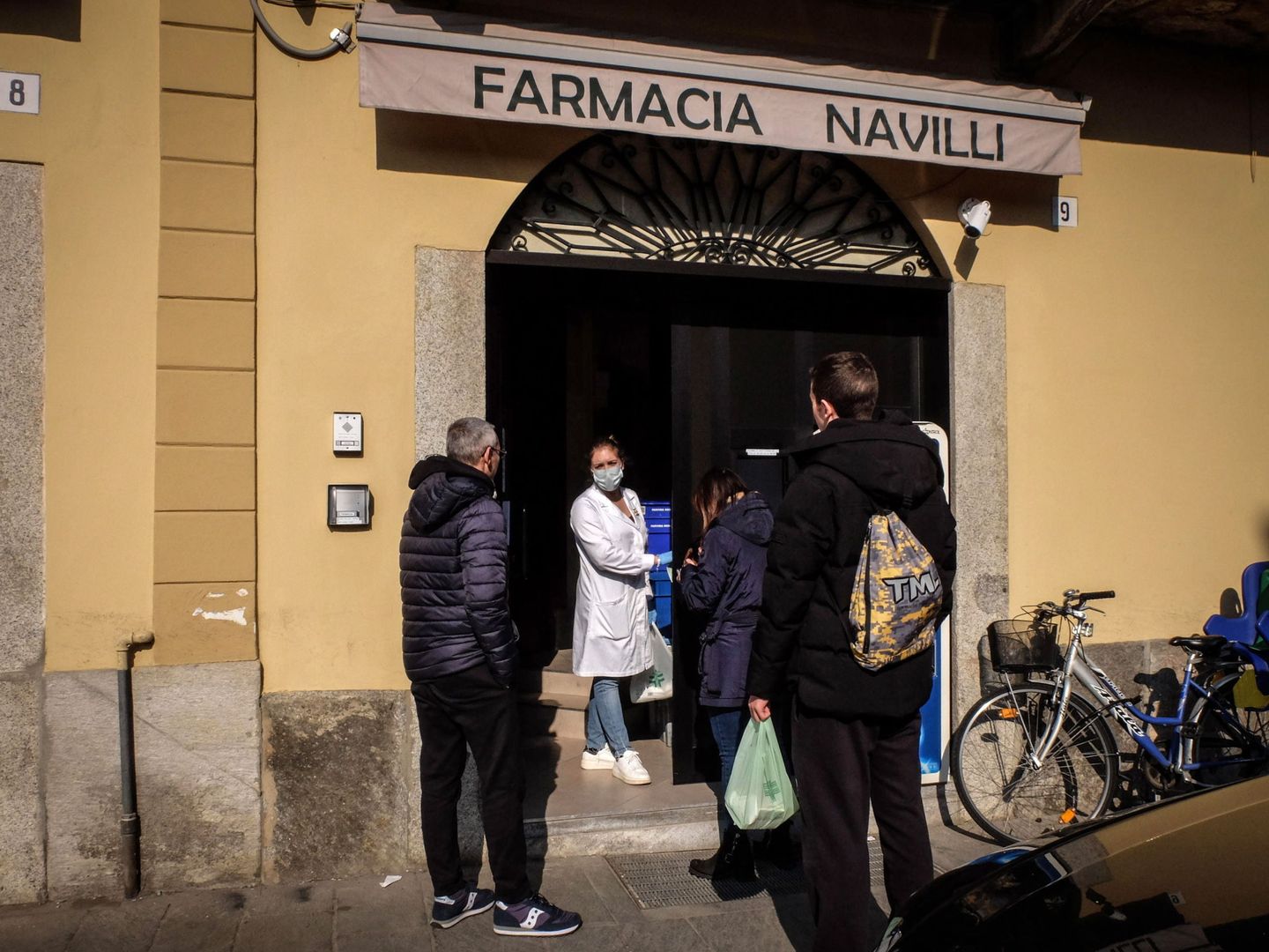 Una farmacéutica con una máscara habla a los clientes en la entrada de una farmacia en Codogno, en Lodi, norte de Italia. (EFE)