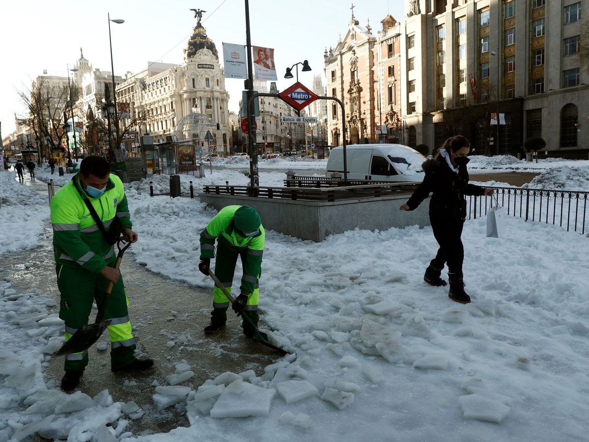 Foto: Unos operarios retiran nieve de la acera este lunes en la calle Alcalá de Madrid. (EFE)