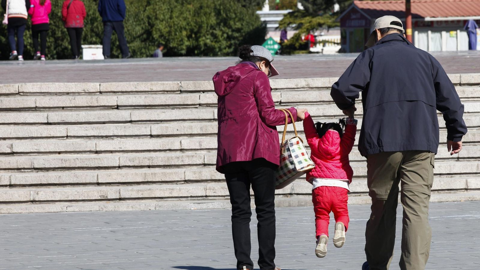 Foto: Dos abuelos sacan de paseo a su nieta en un parque de Pekín (China). (EFE)