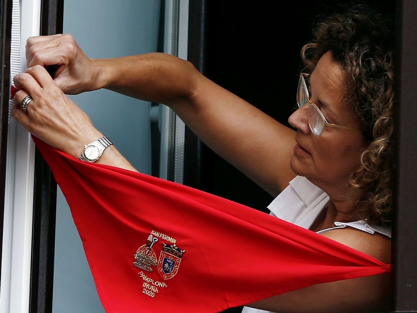 Una mujer coloca el pañuelo de los Sanfermines en la ventana de su vivienda. (EFE)