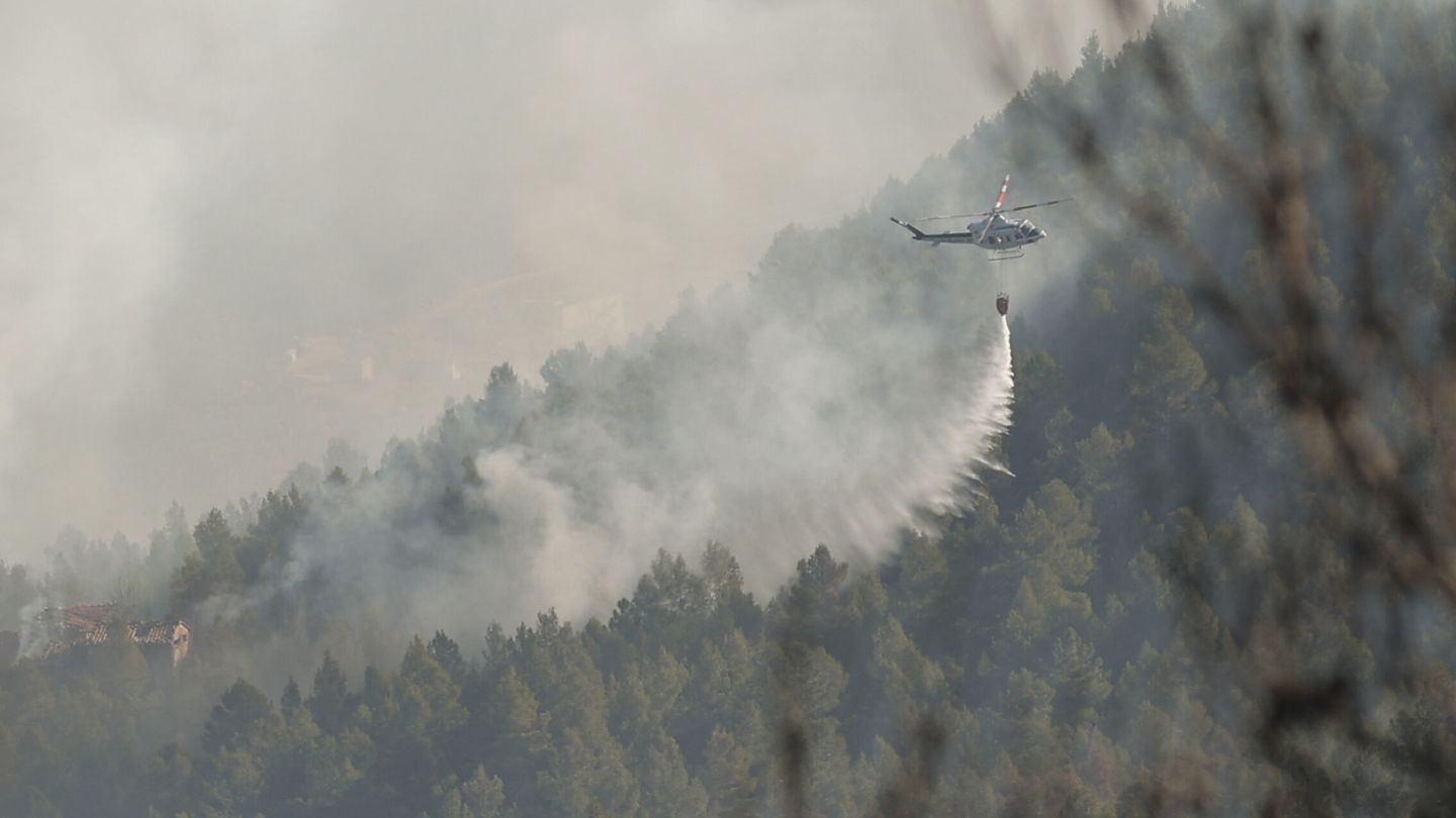 Un helicóptero trabaja en la extinción del incendio. (EFE/Manuel Bruque)