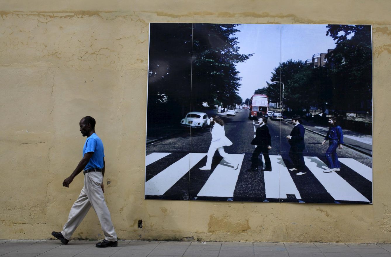 Un caminante pasa frente a una fotografía gigante de los Beatles en Camagüey, Cuba. (Reuters)