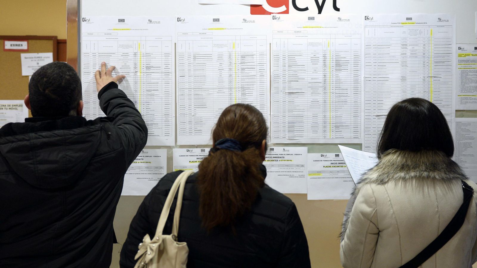 Foto: Tres personas consultan la información expuesta en una oficina de empleo del ECyL de Valladolid. (EFE)