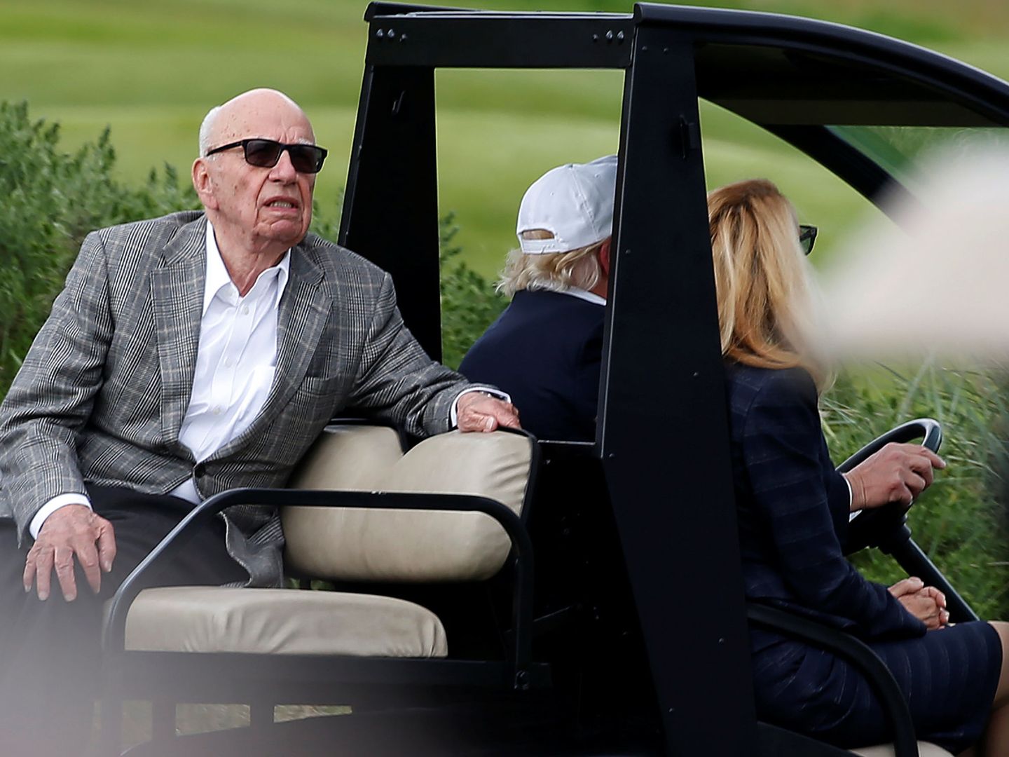Un día inolvidable: Murdoch en un carrito de golf conducido por Trump con Hall de copiloto. (Reuters)