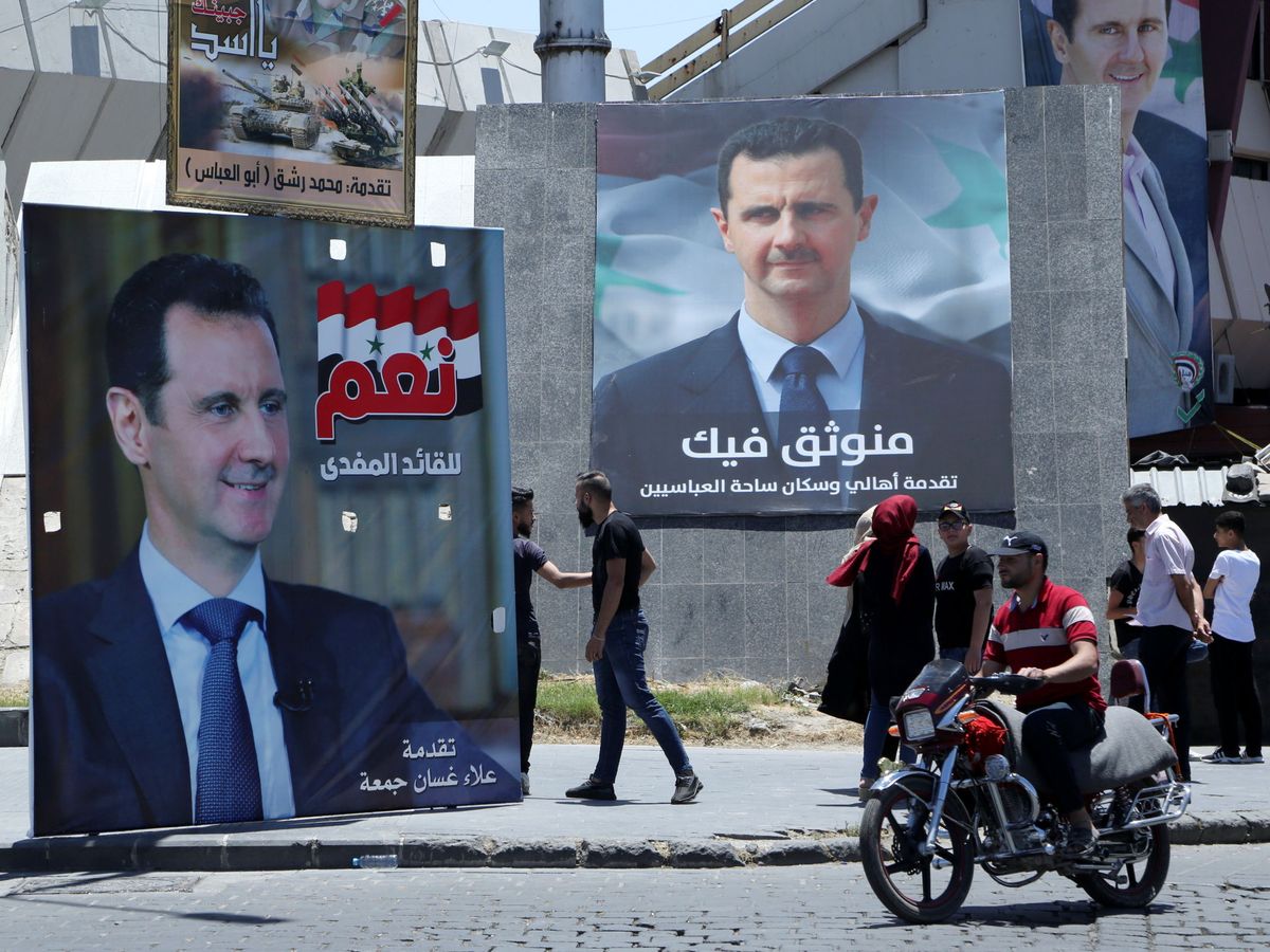 Foto: People stand near posters depicting syria's president bashar al-assad in damascus