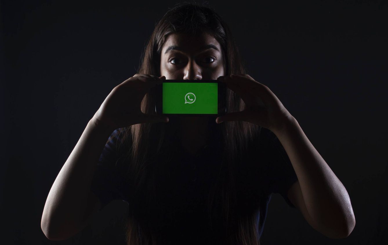 Una mujer sostiene un móvil con el logotipo de WhatsApp. (Unsplash)