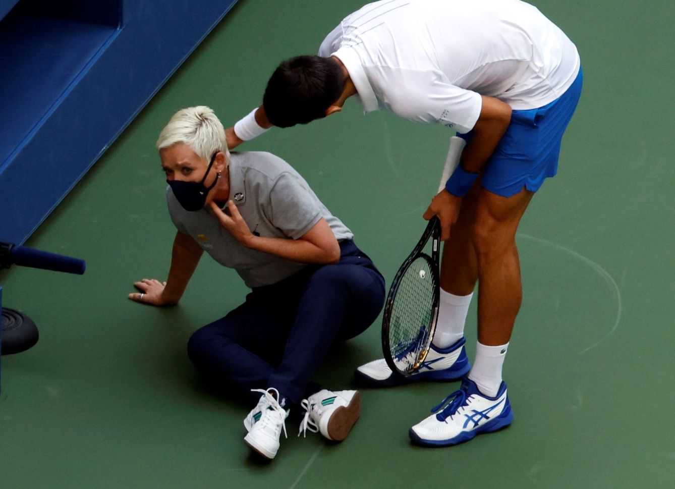 Djokovic intenta ayudar a la juez de línea después de golpearla en la garganta. (Efe)