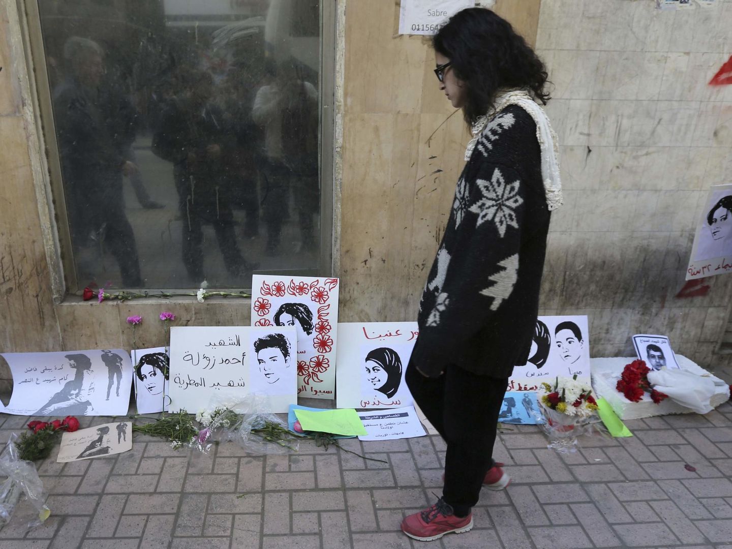 Una mujer observa los carteles de homenaje a la activista Shaimaa Sabbagh, asesinada de un tiro a quemarropa por la policía en El Cairo, en enero de 2015 (Reuters)