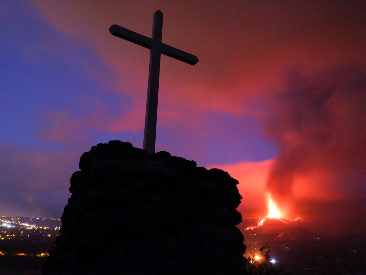 Foto: Un cruz, con la erupción del volcán de fondo. (Reuters)