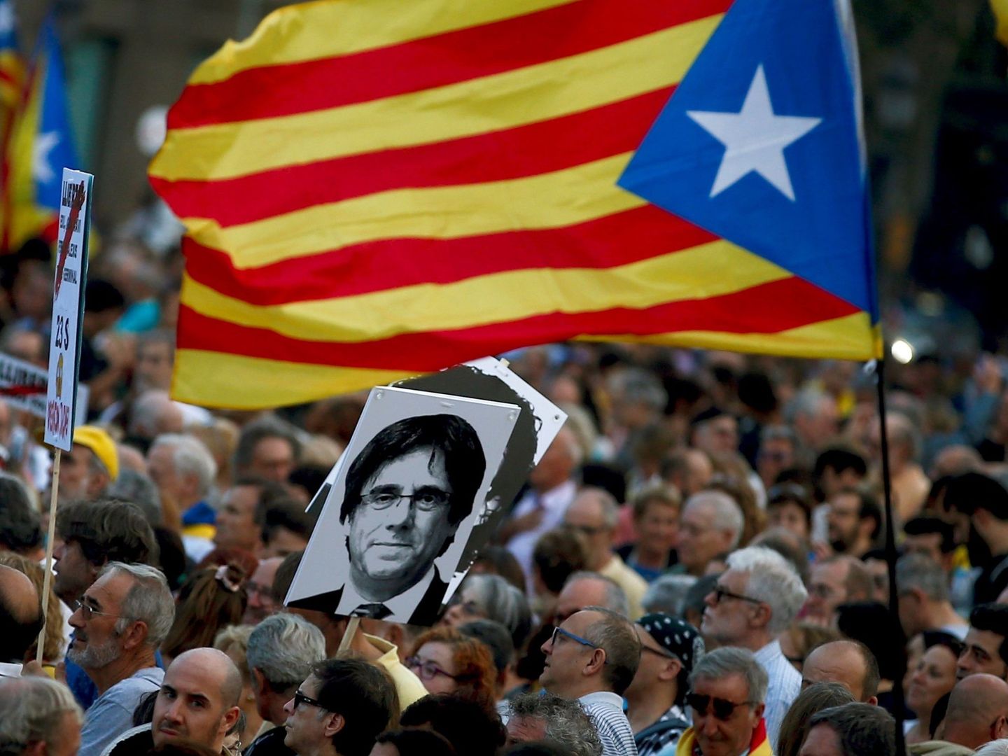 Manifestantes portan una fotografía del 'expresident' de la Generalitat de Cataluña, Carles Puigdemont. (EFE)