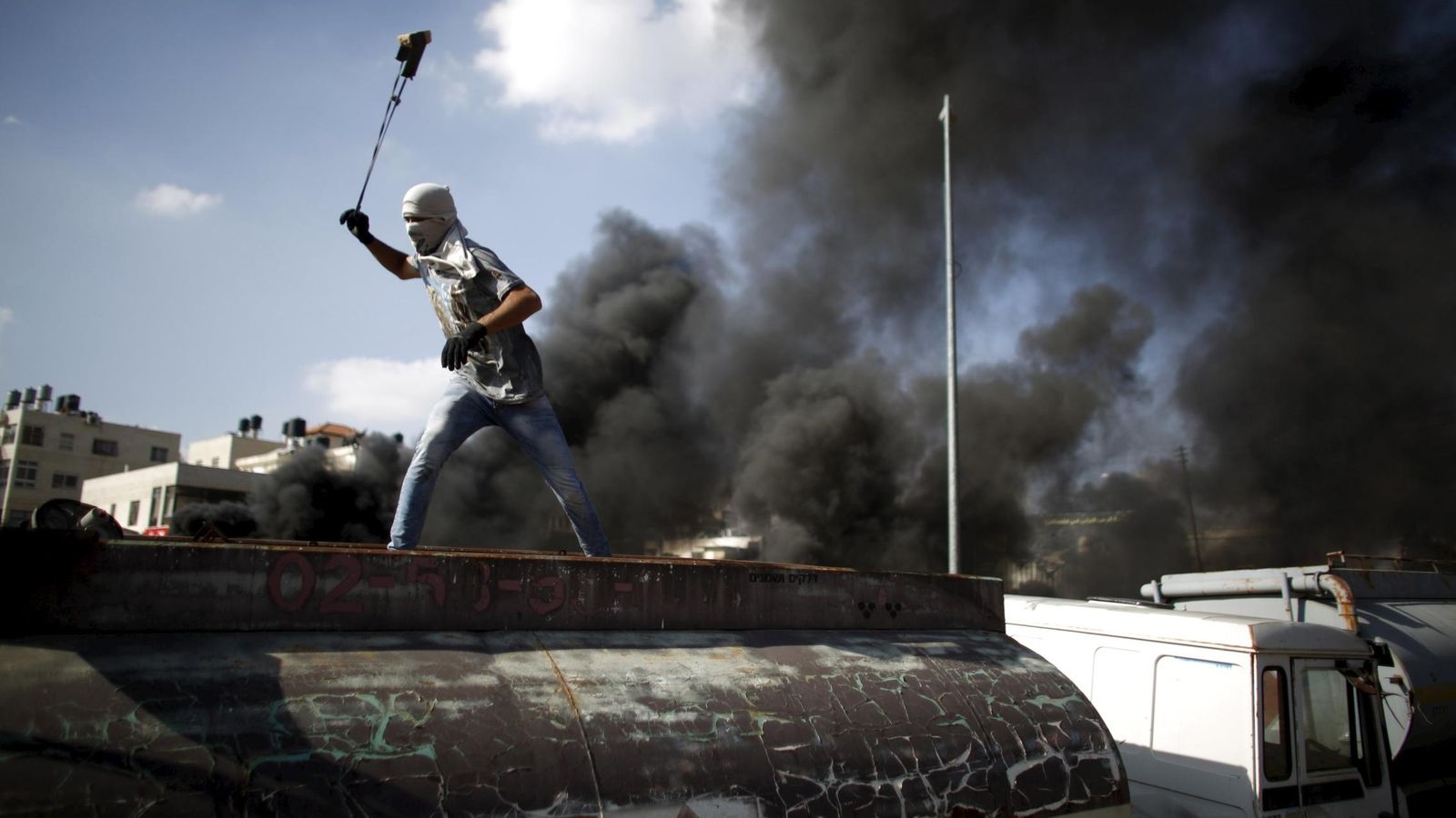 Foto: Un palestino lanza piedras contra soldados israelíes durante enfrentamientos en la colonia judía de Beit El, cerca de Ramala, en Cisjordania (Reuters).