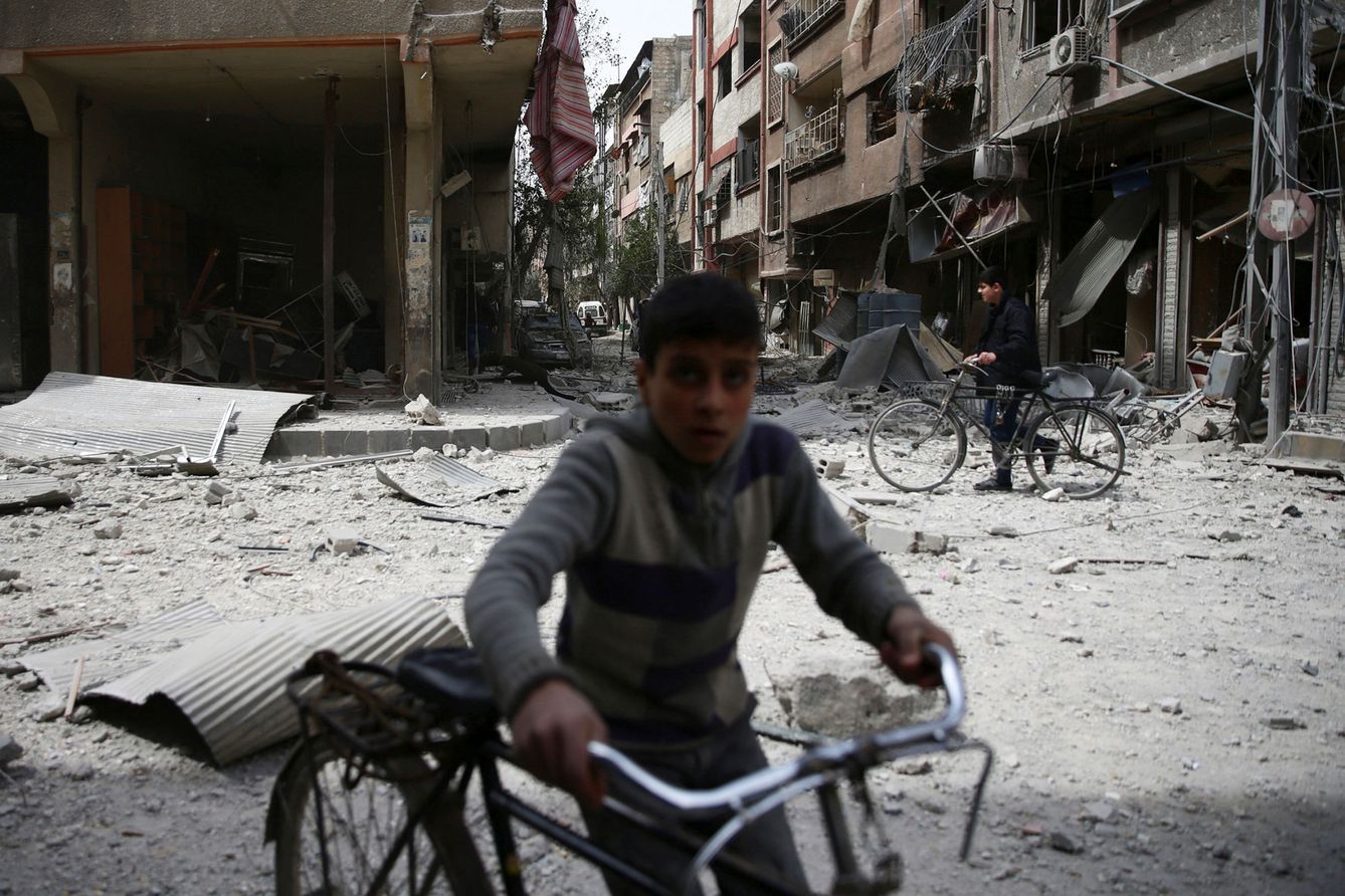 A boy pushes a bicycle at a site hit by an airstrike in the rebel held besieged Douma neighborhood of Damascus, Syria March 27, 2017. REUTERS Bassam Khabieh