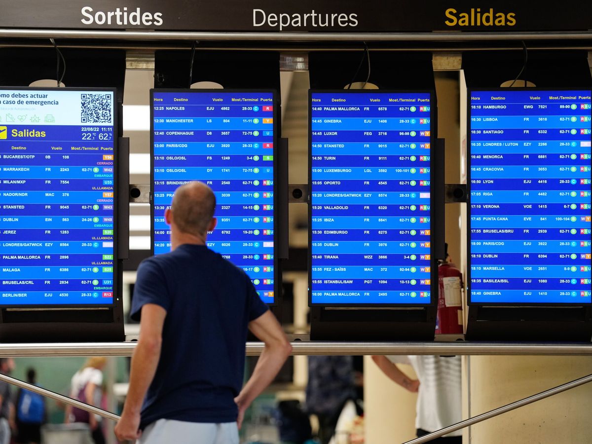 Foto: Un pasajero observa un panel de salidas en el aeropuerto de El Prat. (EFE/Enric Fontcuberta)
