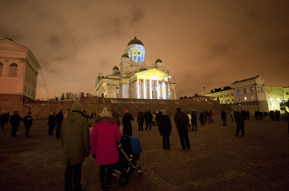Un grupo de personas observa la catedral de Helsinki iluminada (Reuters).