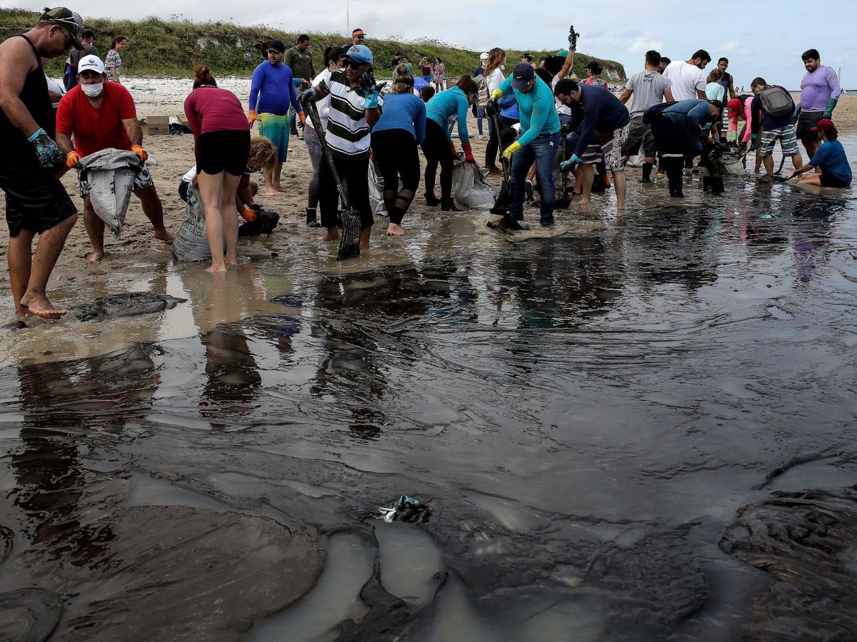 Foto: Voluntarios ayudan este domingo a eliminar la mancha de petróleo que ha llegado a la costa noreste en Cabo Agostinho, estado de Pernambuco (Brasil). (EFE)