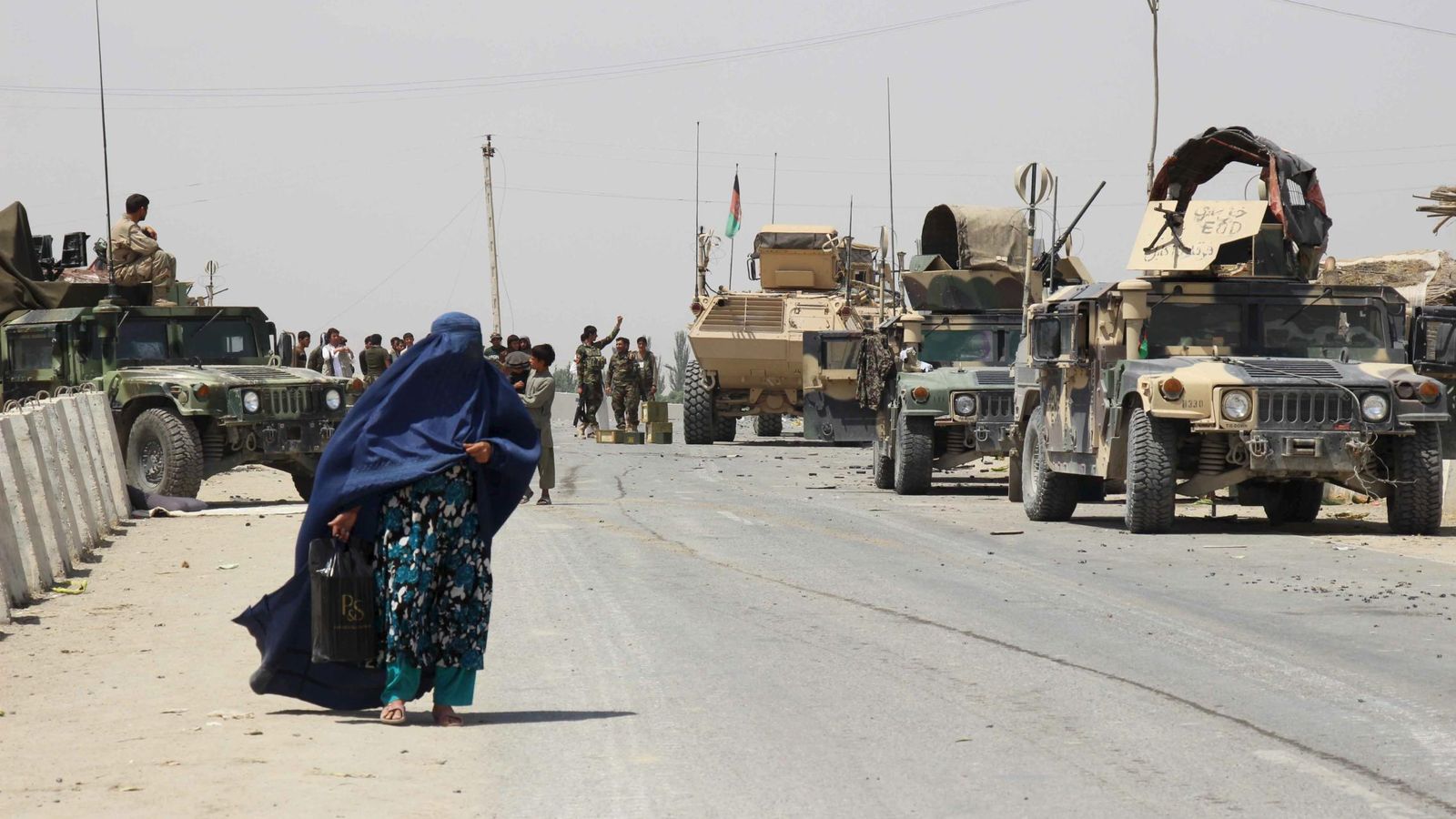 Foto: Una mujer pasa ante vehículos del Ejército afgano en la provincia de Kunduz, distrito de Chardara (Reuters).