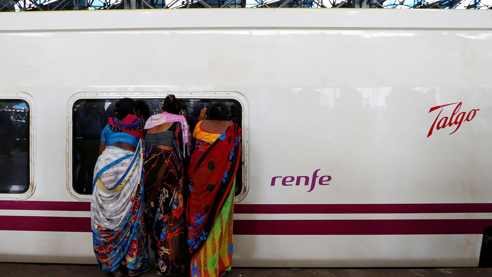 Foto: Gente mira en un tren de Renfe construido por Talgo. (Reuters)