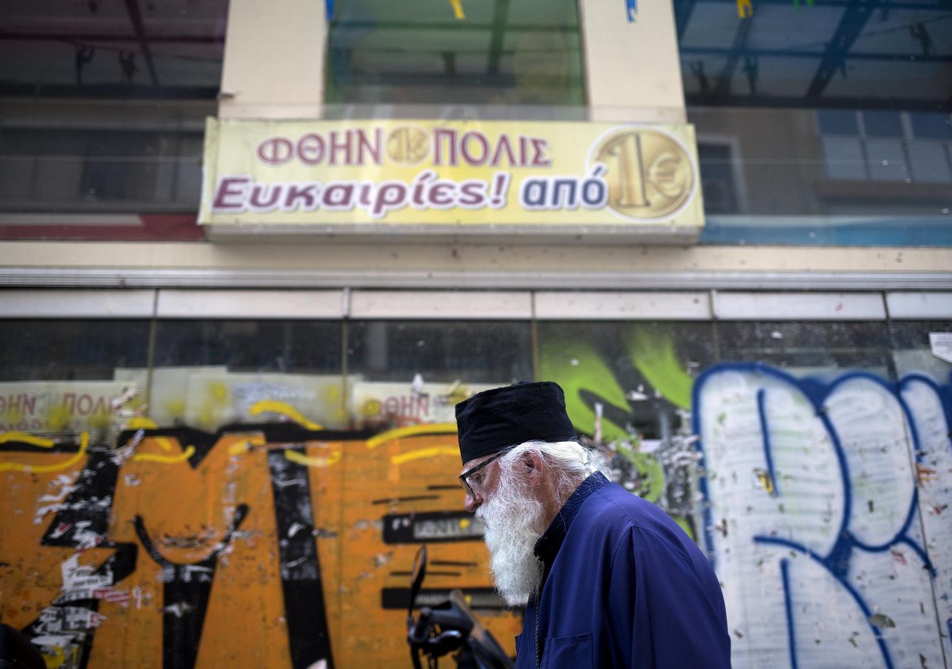 Un sacerdote pasa frente a una tienda cerrada en Atenas, en agosto de 2015 (Reuters)