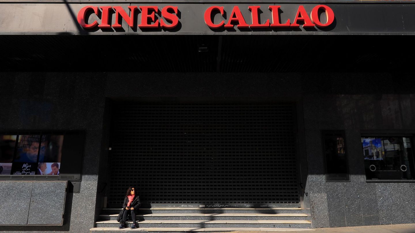 Una mujer descansa junto a los cines Callao en Madrid, cerrados por el coronavirus. (Efe)