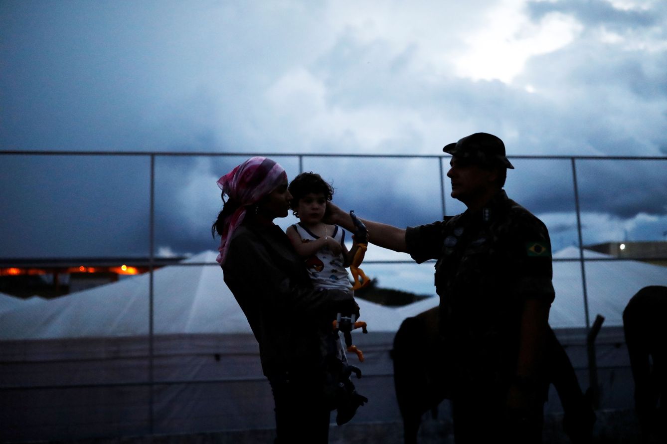 Un teniente del ejército brasileño habla con una venezolana y su hijo tras comprobar sus pasaportes en el paso fronterizo, el 19 de agosto de 2018. (Reuters)