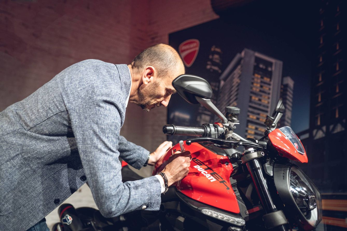 Claudio Domenicali, CEO de Ducati Motor Holding, firma sobre una Ducati Monster.