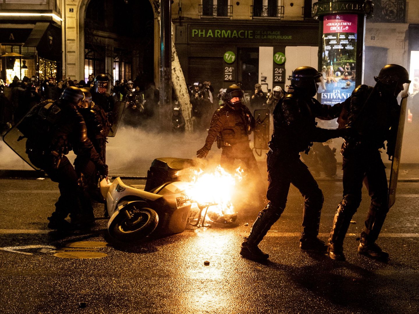 Agentes de policía retiran una moto en llamas durante los disturbios en los Campos Elíseos de París, el 26 de enero de 2019. (EFE)