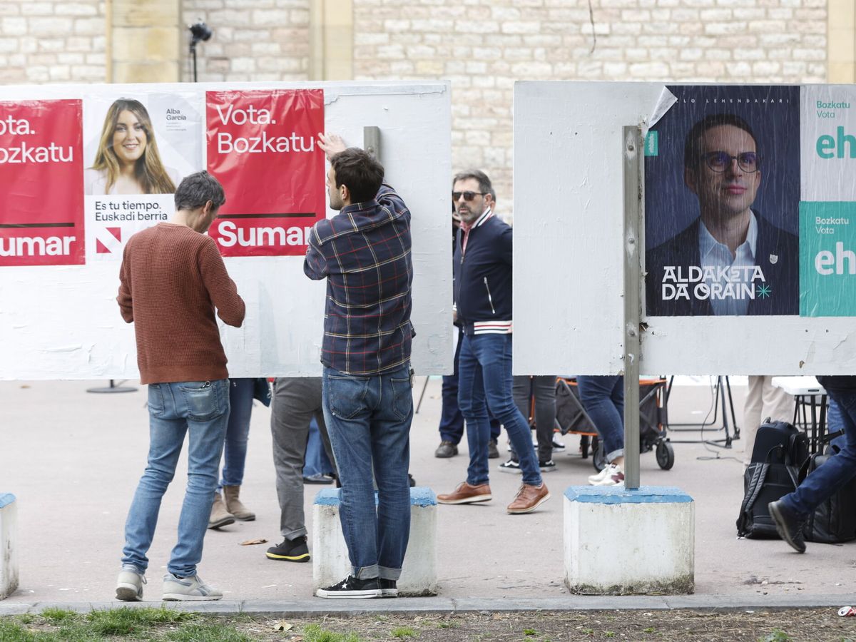 Foto: Unos jóvenes pegan carteles electorales en San Sebastián. (EFE/Juan Herrero)