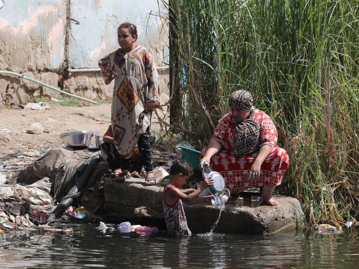 Foto: Mujeres egipcias lavan platos y utensilios mientras voluntarios egipcios recogen los desechos a orillas del río Nilo. (EFE/EPA/Khaled Elfiqi)