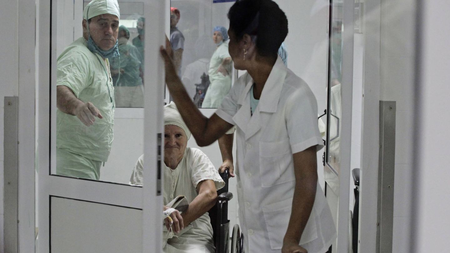 Personal de un hospital en Cienfuegos ayudan a una paciente en silla de ruedas tras una cirugía, en febrero de 2013. (Reuters)