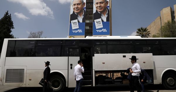 Foto: Varios ultraortodoxos junto a un autobús y bajo un póster electoral de Netanyahu. (Reuters)