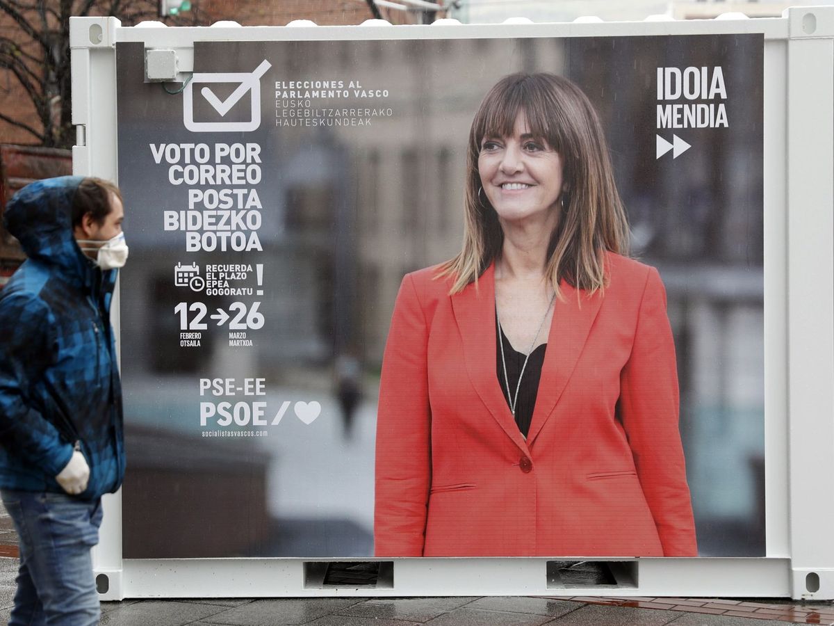 Foto: Un ciudadano con mascarilla, pasa por delante de un cartel preelectoral en Bilbao. (Efe)