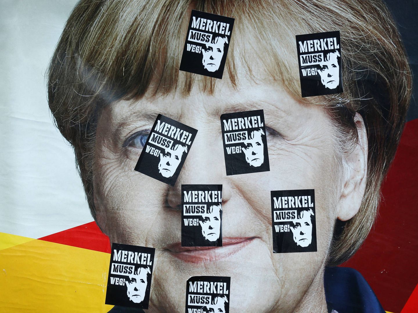 Un cartel electoral de la canciller con pegatinas que rezan: 'Merkel debe irse', en Fráncfort. (Reuters)