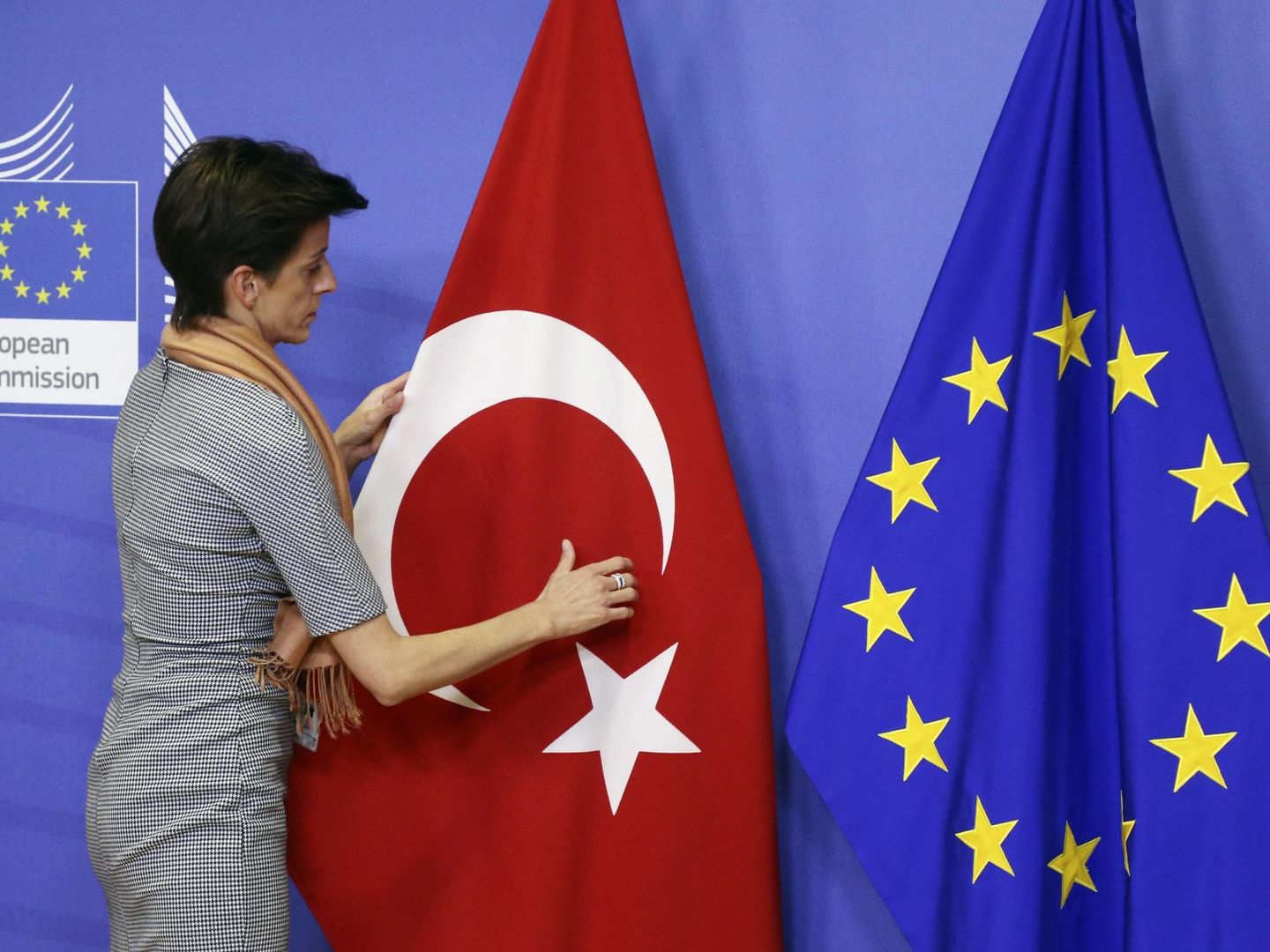 Una trabajadora de la Comisión Europea sitúa una bandera turca junto a una europea antes de una visita de un cargo turco al Ejecutivo comunitario. (Reuters)