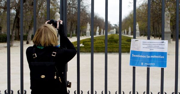 Foto: Una mujer toma una instantánea desde una de las puertas del parque del Retiro, cerrado por el Ayuntamiento de Madrid hasta el próximo viernes. (EFE)