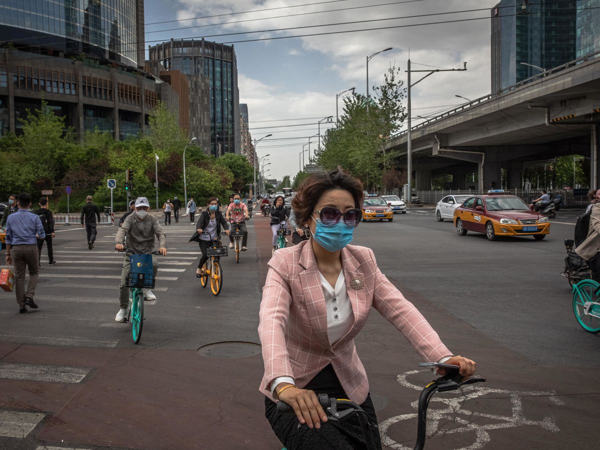 Foto: Ciclistas con mascarillas en China. (EFE)