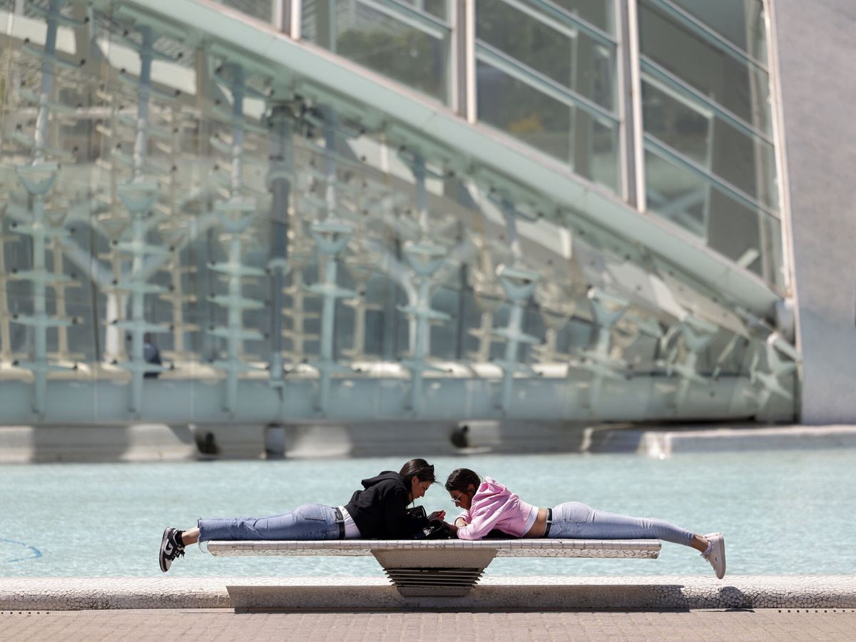 Foto: Dos personas descansas al sol en Valencia. (EFE/Biel Aliño)