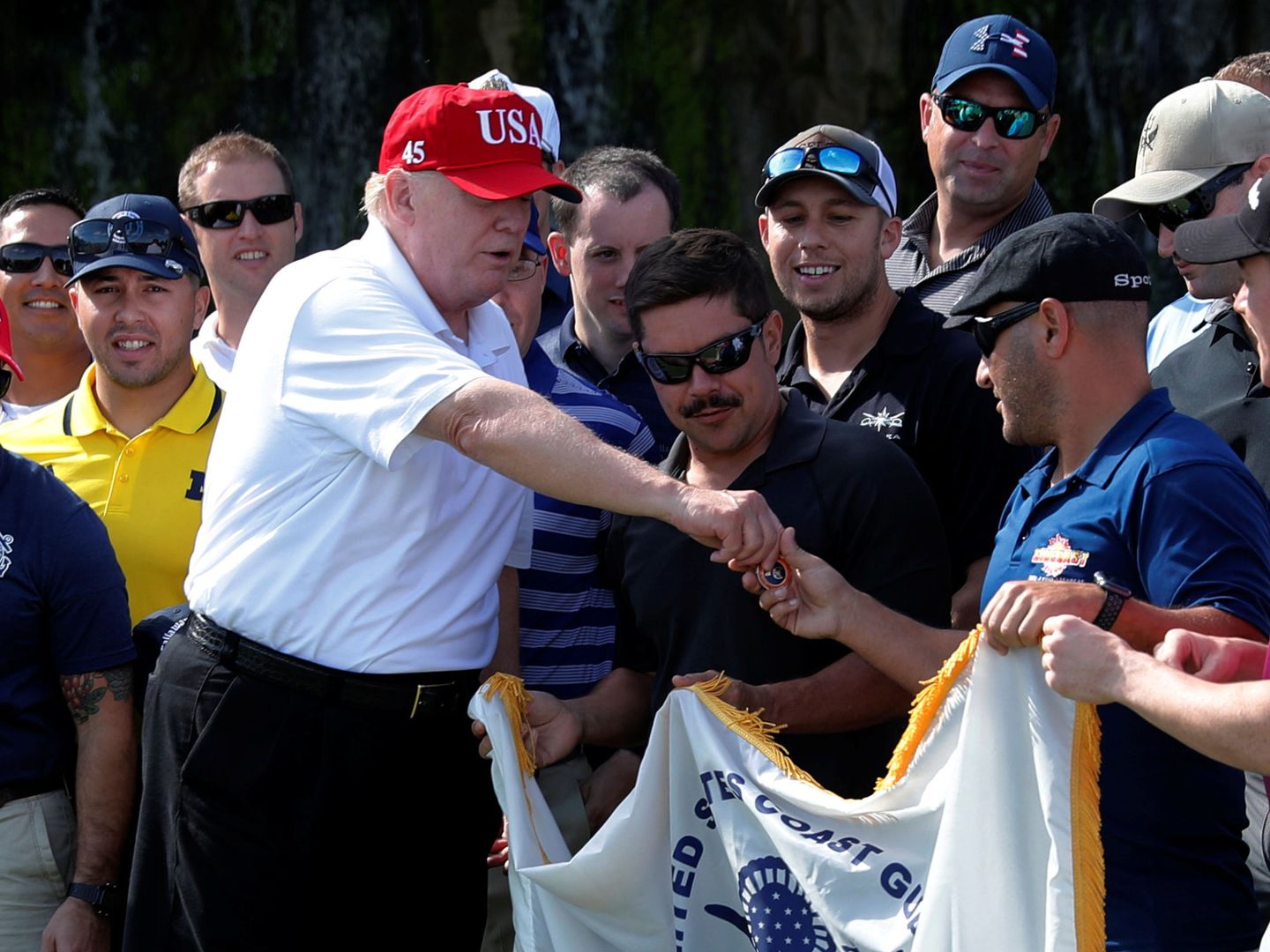 El presidente Donald Trump saluda a miembros de los Guardacostas, invitados a jugar al golf en el Club Internacional Trump en West Palm Beach, Florida, el 29 de diciembre de 2017. (Reuters)
