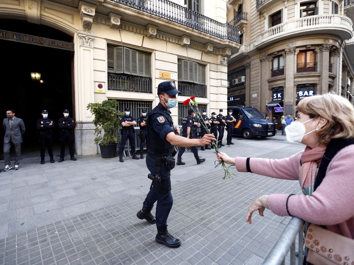 Foto: Una mujer tiende un ramo de claveles a un agente de policía en la sede de la Jefatura Superior de Policía de Barcelona. (EFE/Alejandro García)