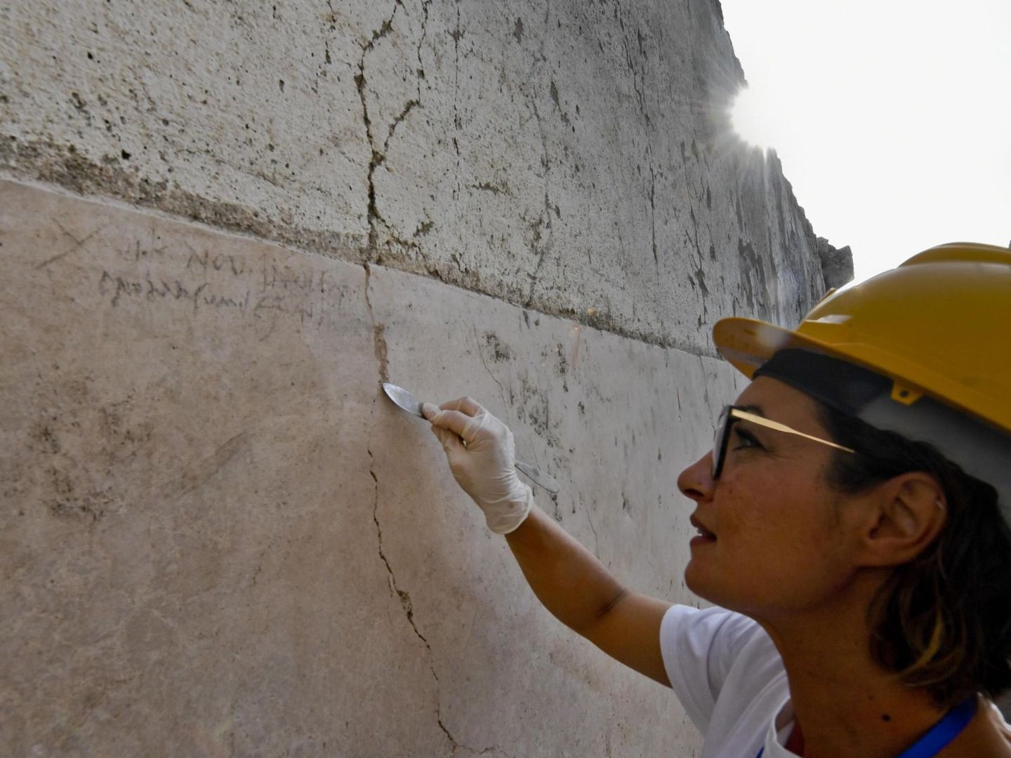 Una arqueóloga señala la inscripción de una pared encontrada en una excavación en Pompeya que acaba finalmente con la duda histórica sobre la fecha de la erupción del Vesubio que sepultó a la ciudad (EFE)