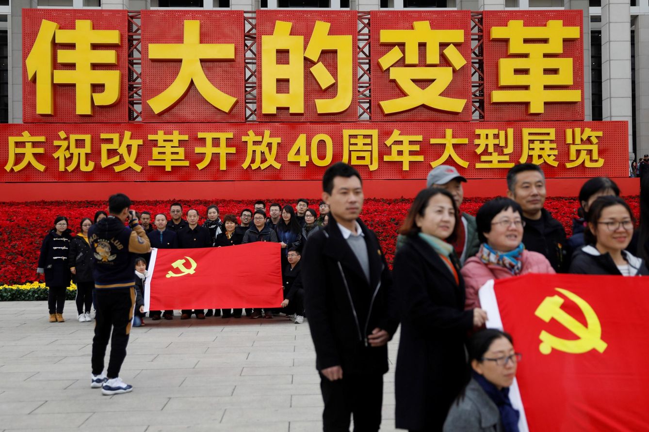 Visitantes sostienen banderas del Partido Comunista deltante de una exposición. (EFE)