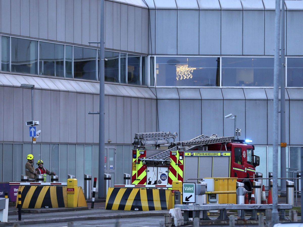 Foto: Varios trabajadores operan en una de las terminales de aeropuerto de Edimburgo. (EFE/Andrew Milligan)