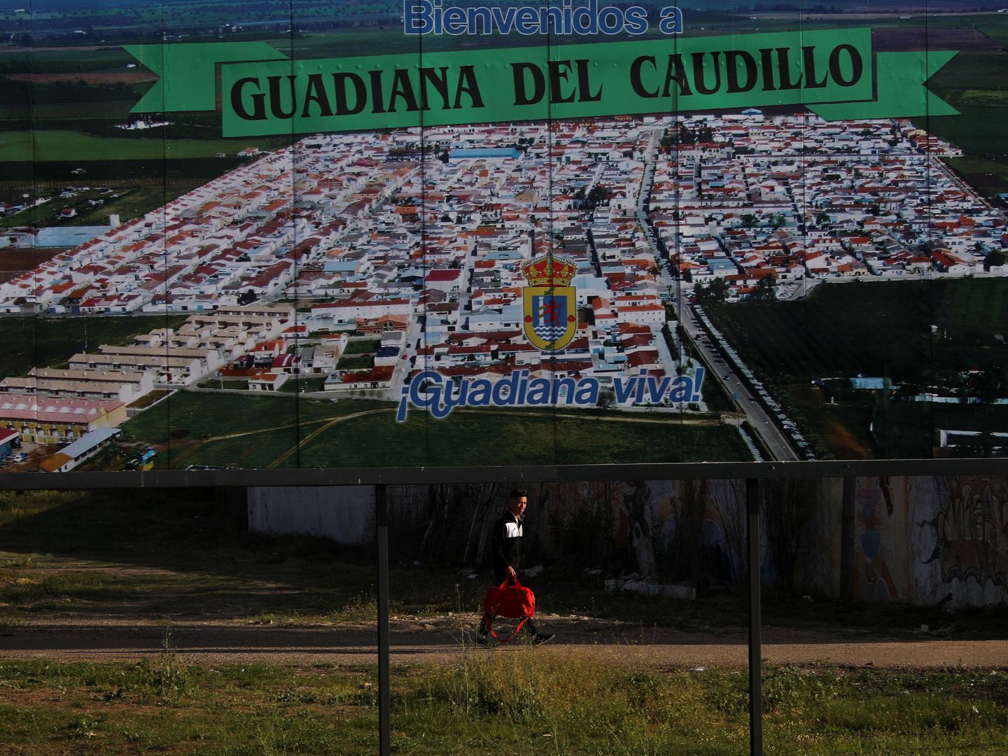A man walks past a welcome sign at the entrance to Guadiana del Caudillo, Spain, March 30, 2019. Picture taken March 30, 2019. REUTERS Susana Vera