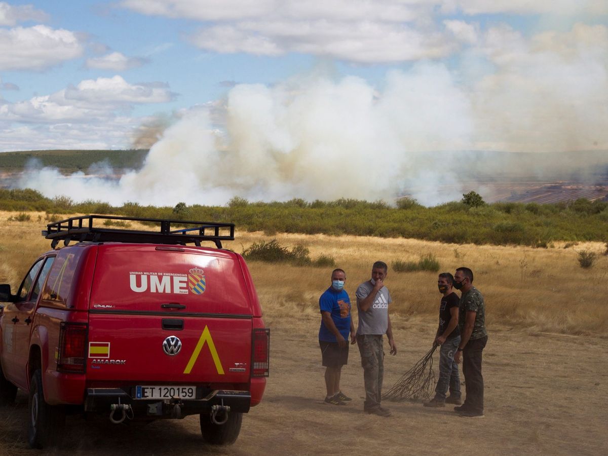 Foto: Vecinos de la localidad zamorana de Vegalatrave junto a un vehículo de la UME ante el incendio forestal declarado ayer en Lober de Aliste (Zamora). (EFE)